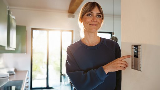 Frau lächelt und passt Thermostat an. Symbolisiert Kosteneinsparung und Energieeffizienz durch gute Heizungsberatung.