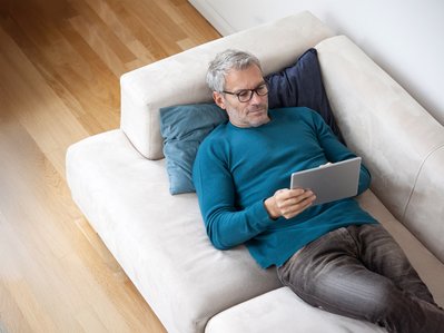 Mann mit Tablet auf Sofa, informiert sich über ENTEGA Kündigungsdetails und Vorteile.