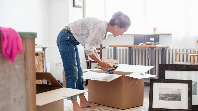 Bild zeigt eine Frau beim Ausräumen von Umzugskisten – ein Umzug ist auch der richtige Zeitpunkt, sich um die Stromanmeldung zu kümmern.