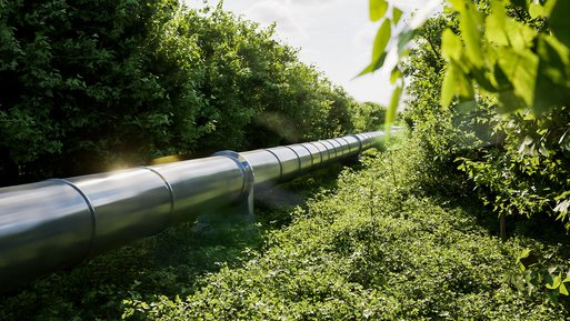 Große isolierte Leitung verläuft durch grüne Landschaft. Transportiert erhitztes Wasser für Fernwärme in Haushalte.