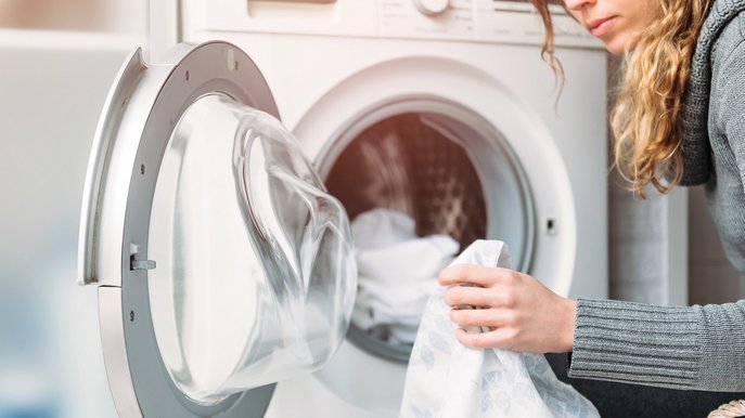 Bild zeigt Frau beim Beladen der Waschmaschine – effizientes Waschen hilft, Strom und Kosten zu sparen.