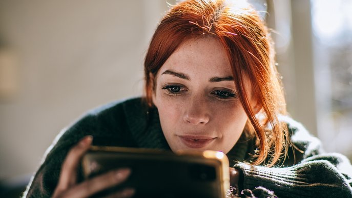 Bild zeigt Frau, die auf ihr Handy schaut – Thema: Stromverbrauch mit einer App messen und verfolgen.